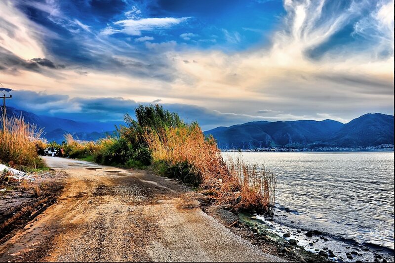 Dirt road by the lake at sunset