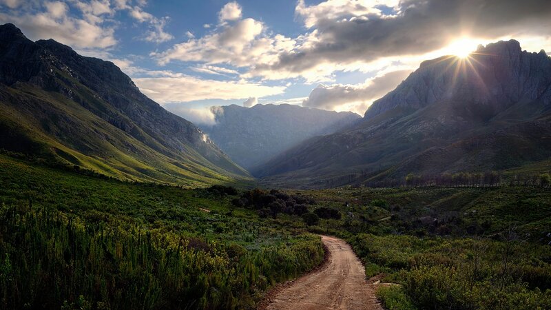 Dirt Road in Mountain Valley — Green, Serene, Sunset