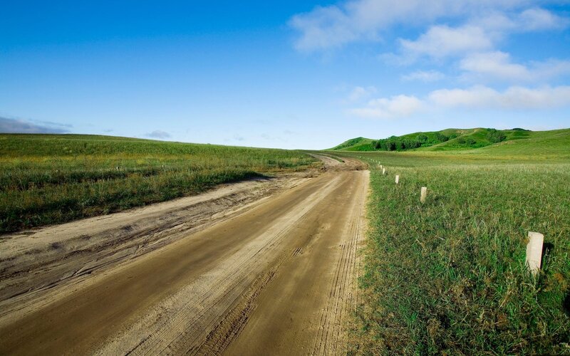 Dirt road through green hills