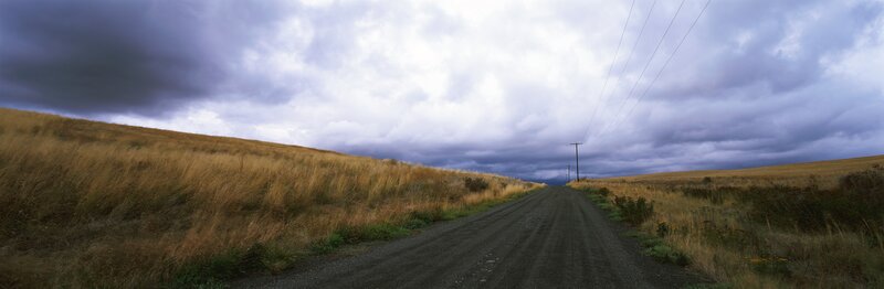Dirt road under stormy sky