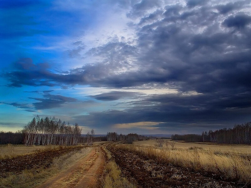 Dirt road under stormy sky
