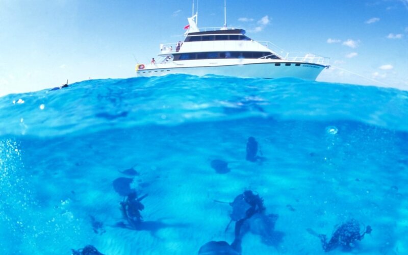 divers exploring ocean near yacht
