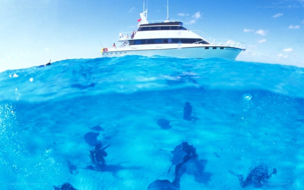 divers exploring ocean near yacht