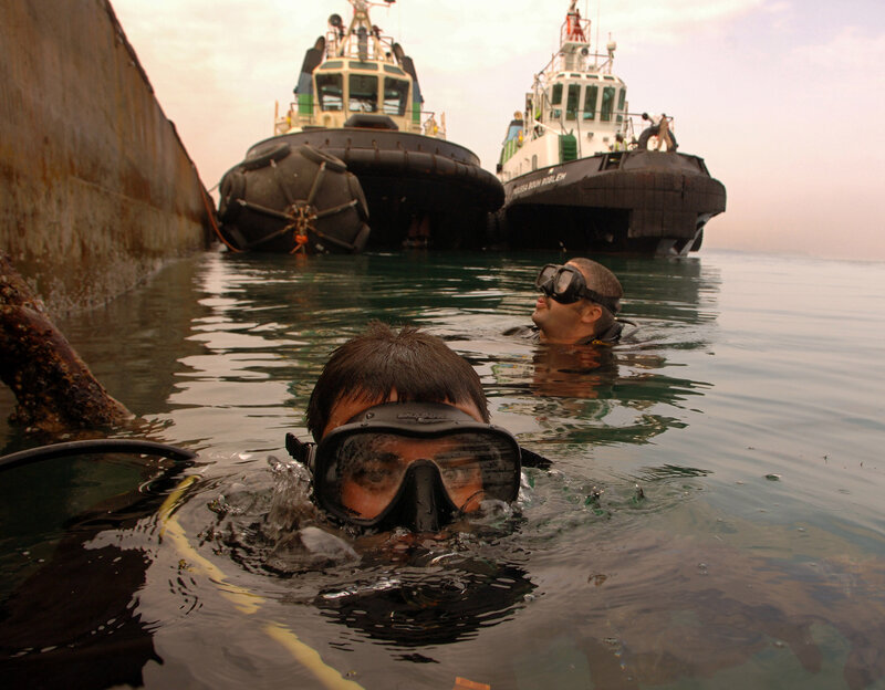 Divers near tugboats in harbor