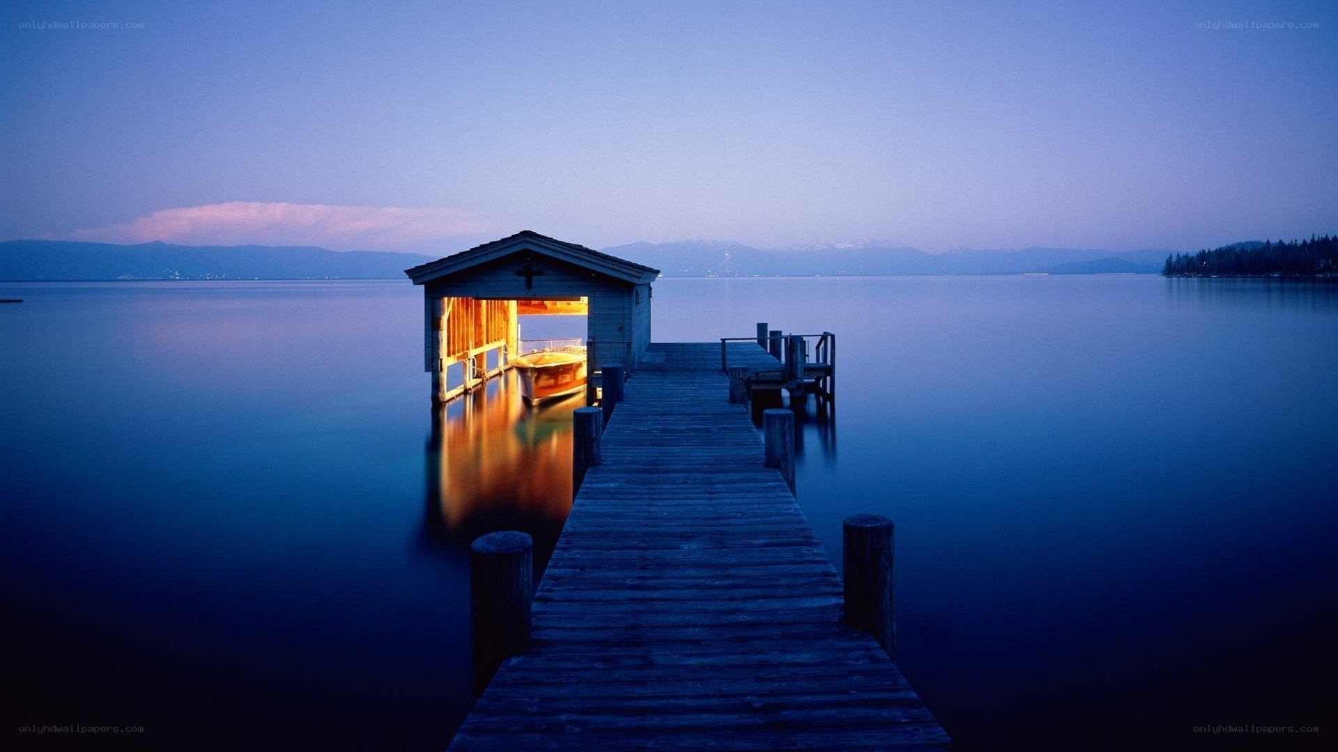 Dock at dusk with lit boathouse