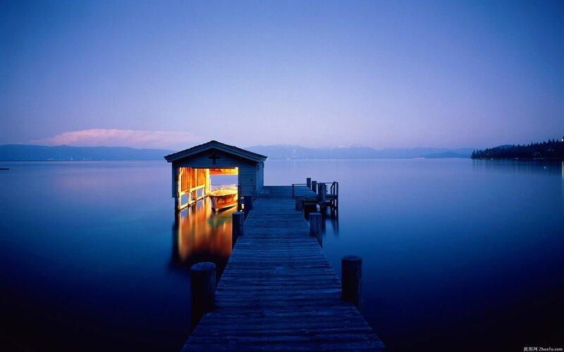 Dock at dusk with lit boathouse