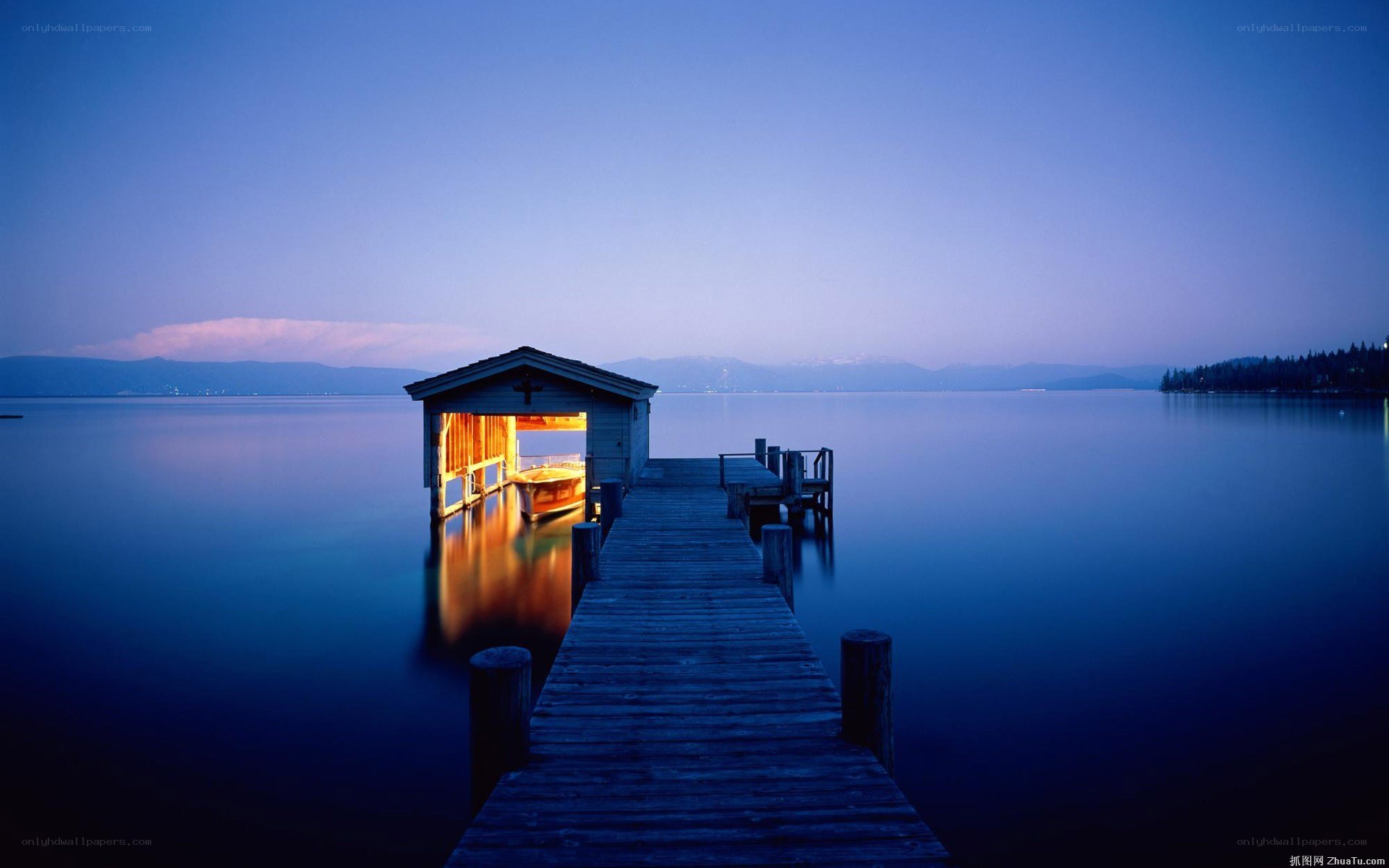 Dock at dusk with lit boathouse
