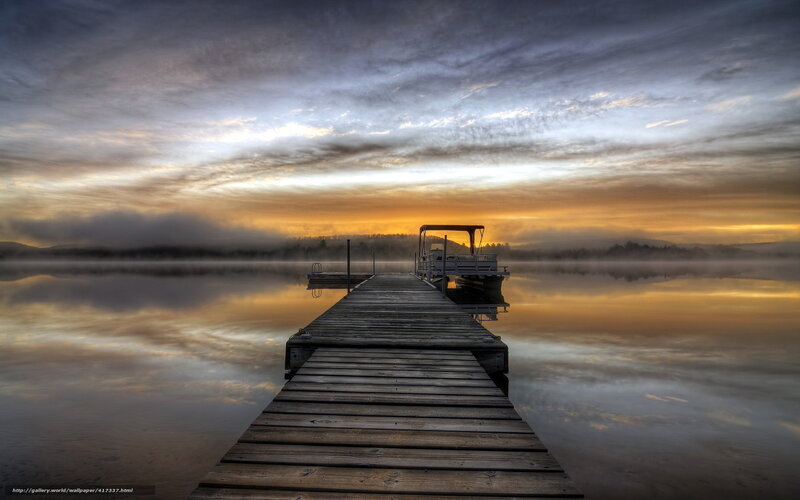 Dock at sunrise over misty lake