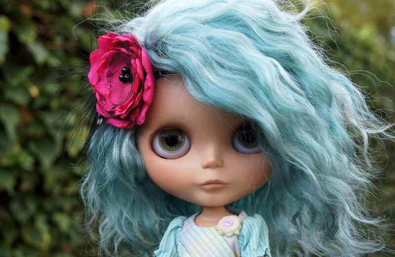 doll with blue hair and pink flower