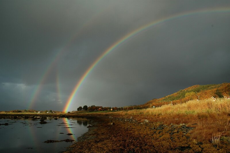 Double rainbow over coastal landscape