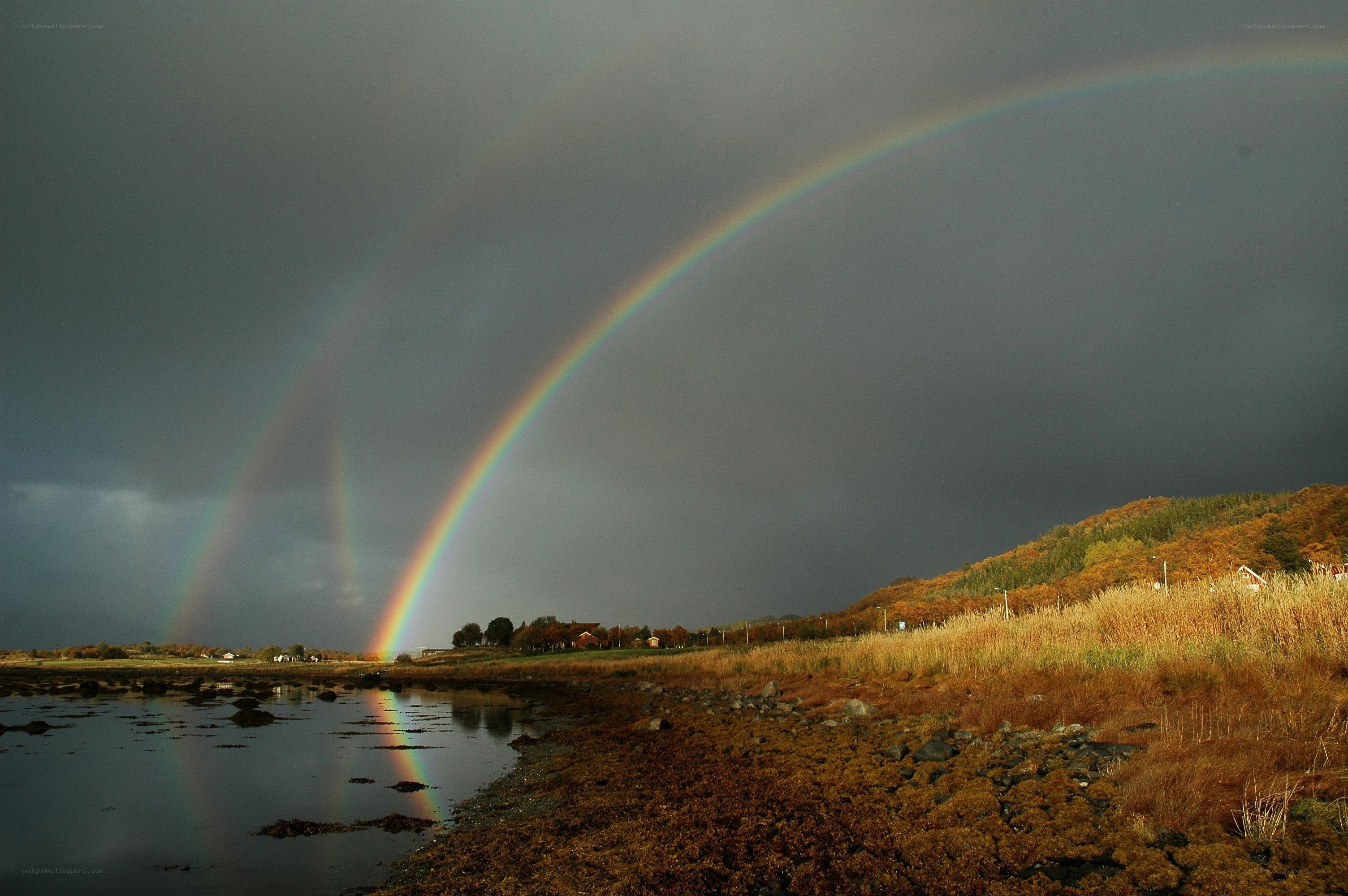 Double rainbow over coastal landscape