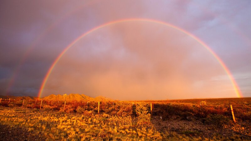 Double rainbow over desert landscape