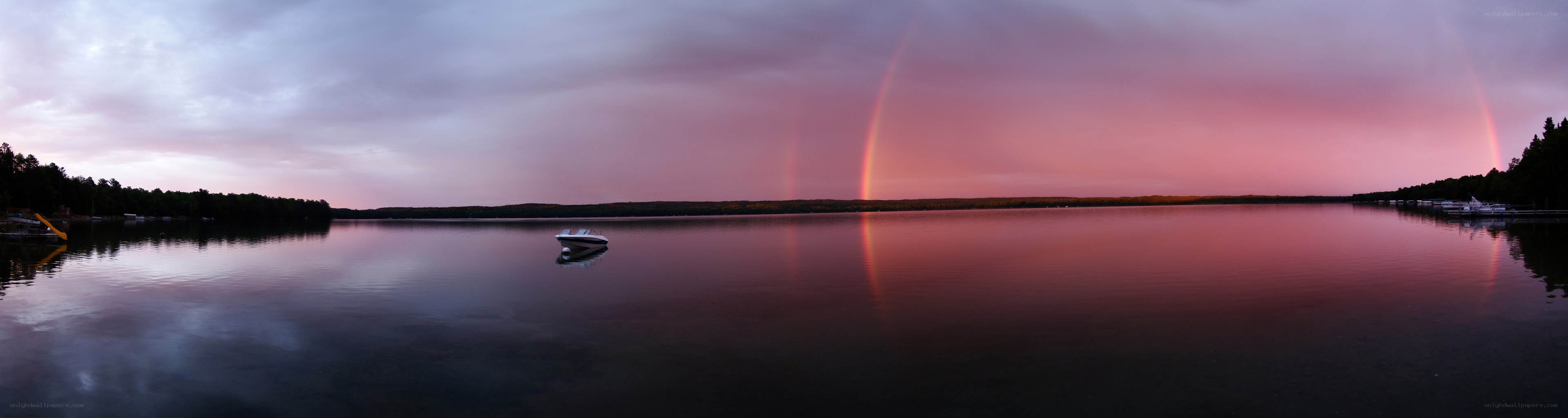 Double rainbow over lake at dusk