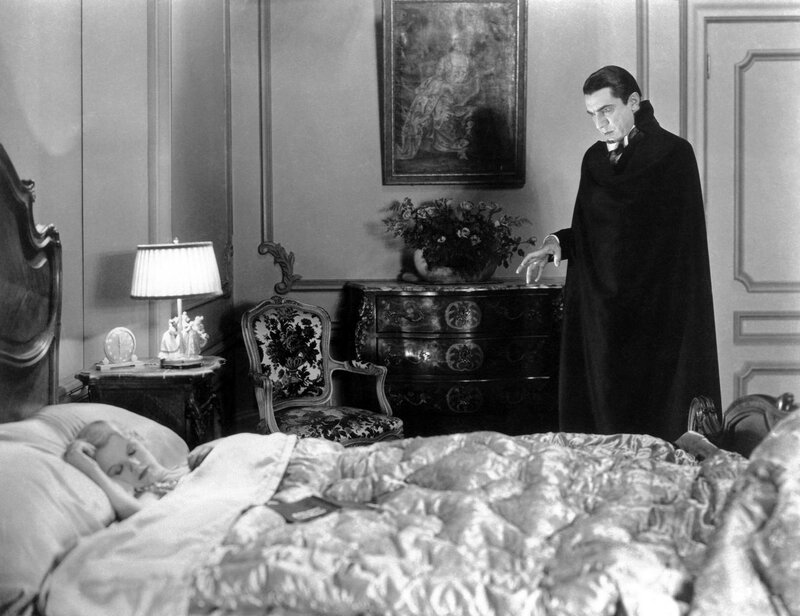 Dracula stands over sleeping woman