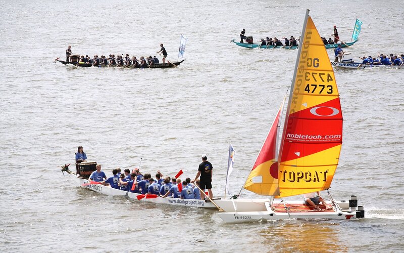 Dragon boats and sailboats on water