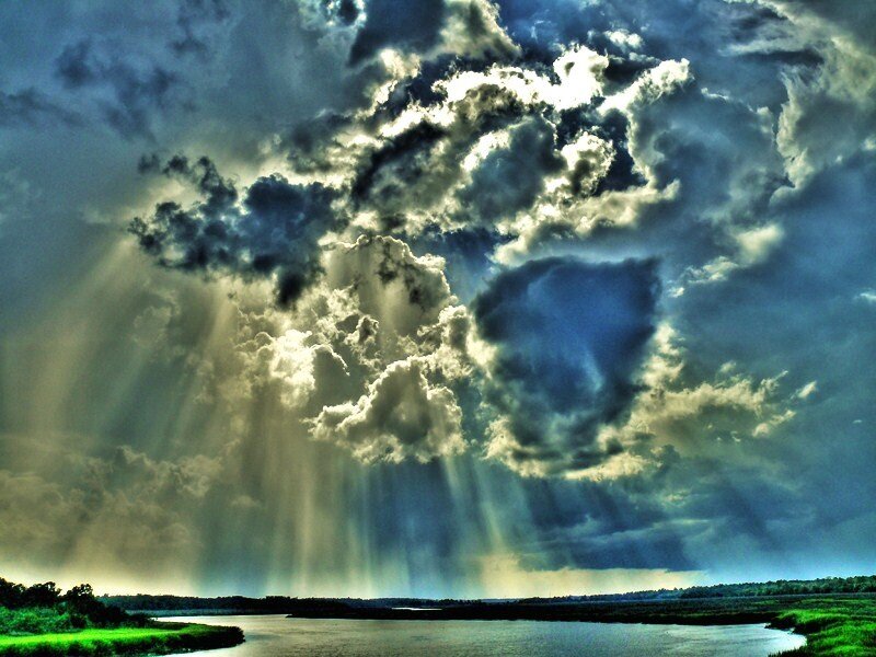 Dramatic sky with sunbeams over water