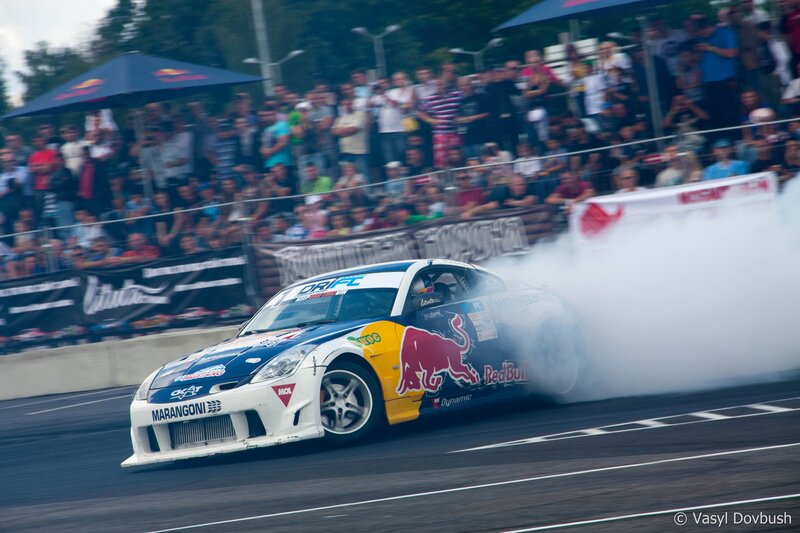 Drifting Race Car — White, Dynamic, Afternoon, Photograph, Crowd, Smoke, Umbrella