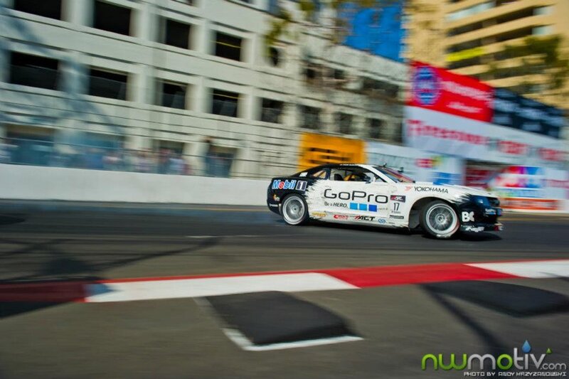 Drifting Race Car — White, Dynamic, Afternoon, Photograph, Race Track, Buildings