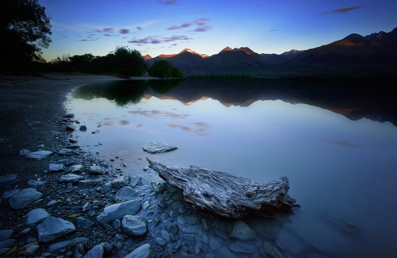 Driftwood on Lake Shore — Blue, Serene, Sunset, Photograph, Mountains