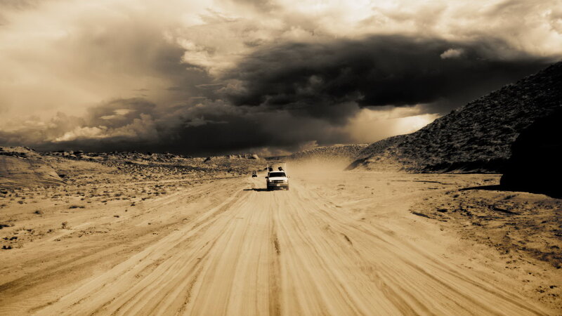 Dusty desert road under stormy sky