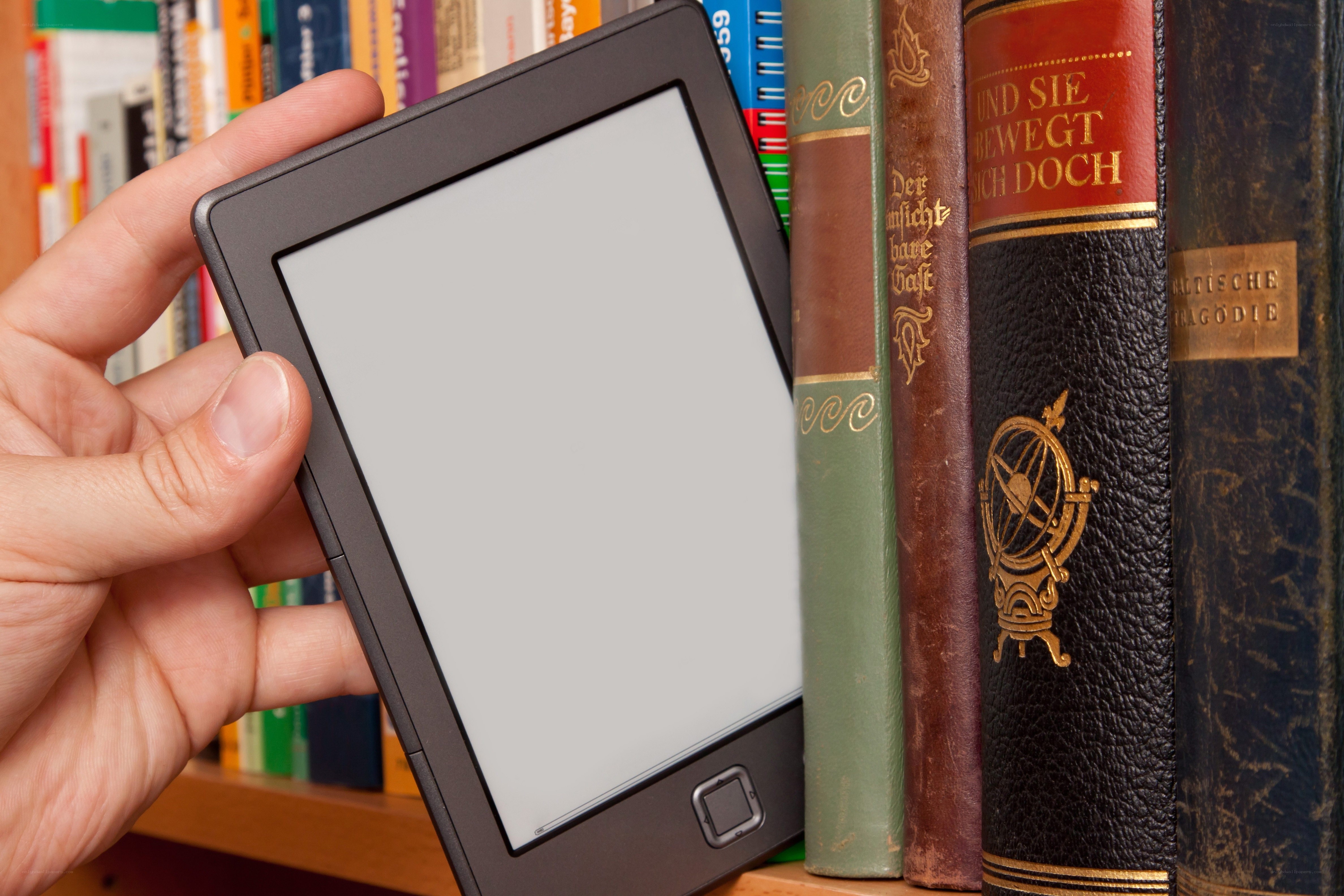 e-reader in hand near books