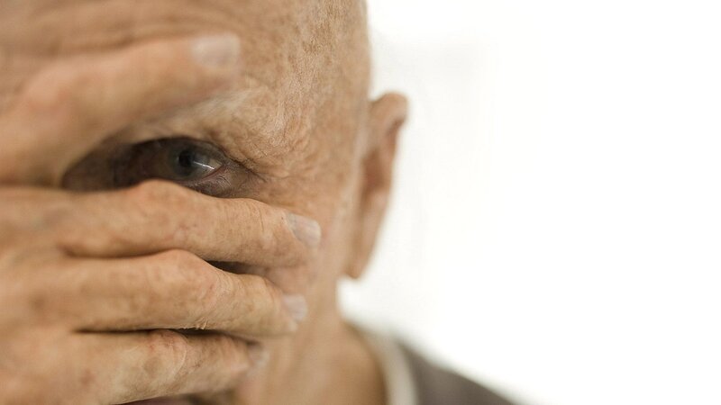 elderly man covering face