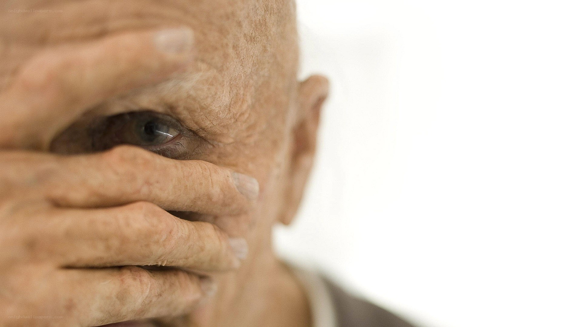 elderly man covering face