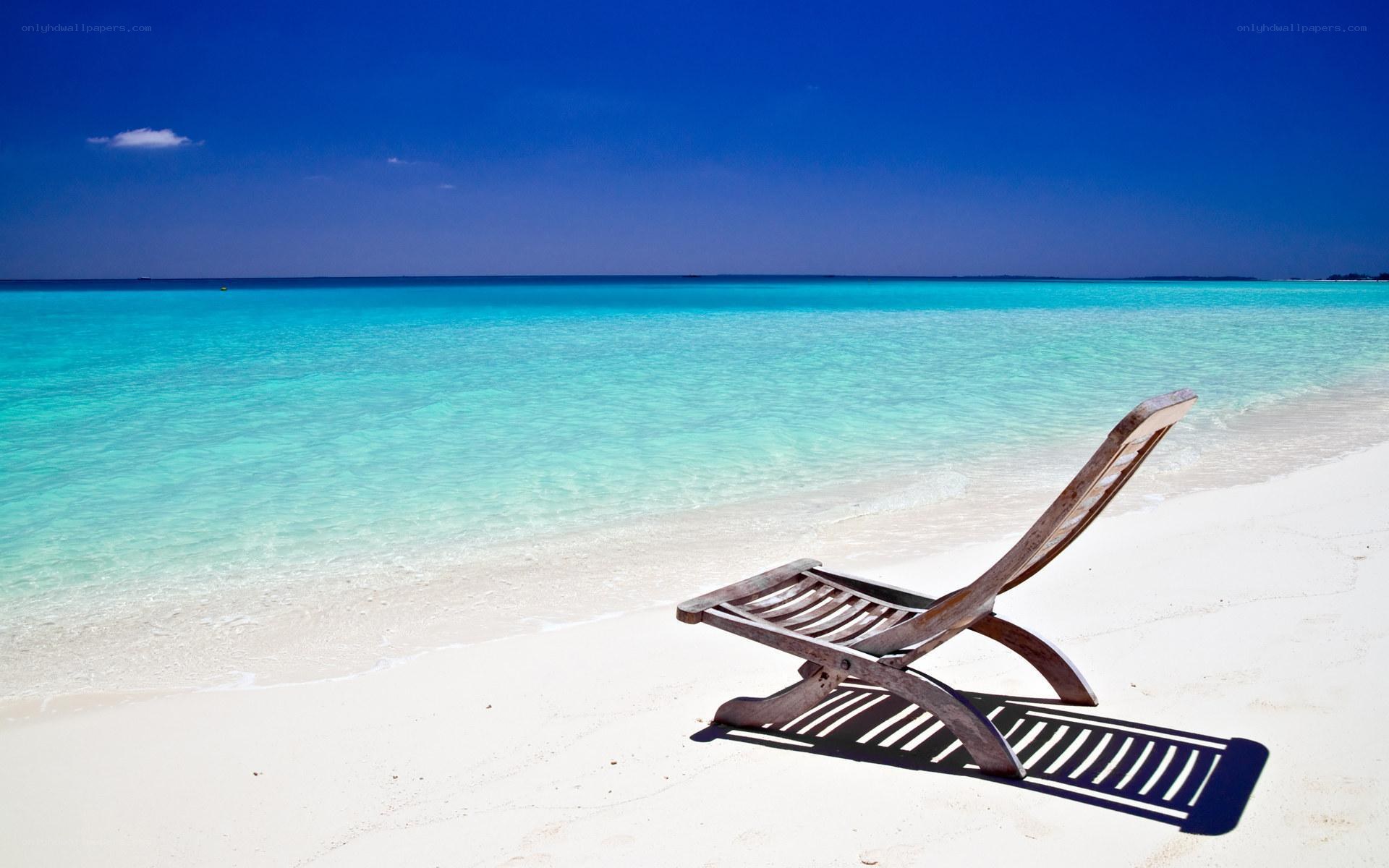 Empty beach chair by turquoise water