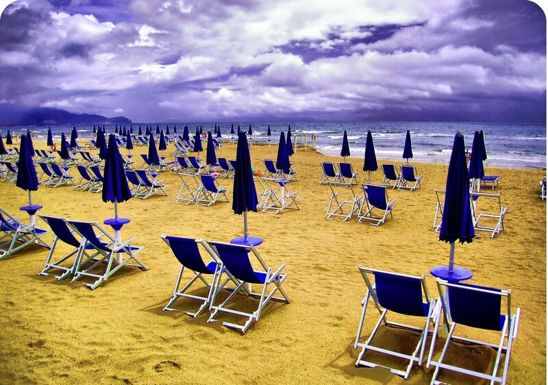 Empty beach chairs under cloudy sky