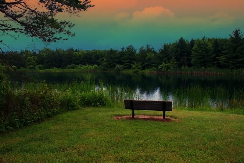 Empty bench by a lake at sunset