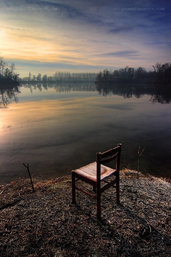 Empty chair by the lake at sunset
