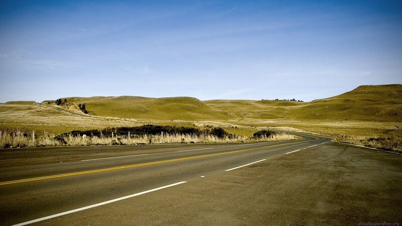 Empty road through green hills