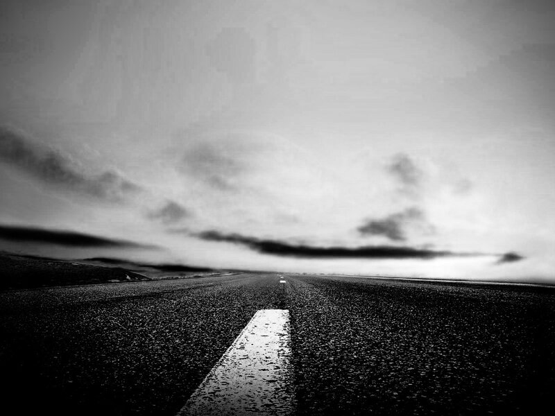 Empty road under cloudy sky
