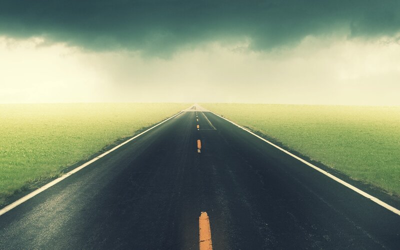 Empty road under stormy sky