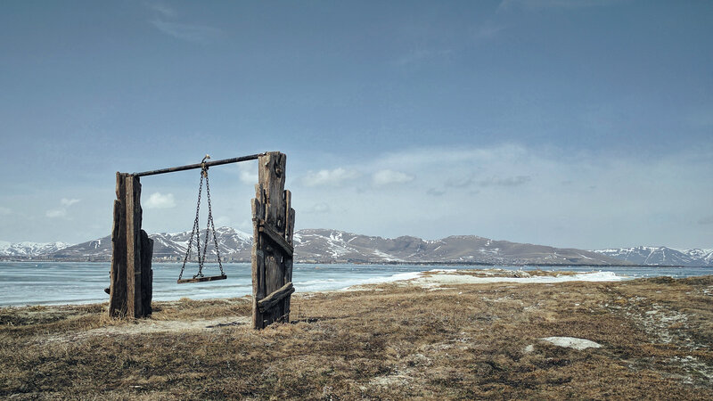 Empty swing by frozen lake