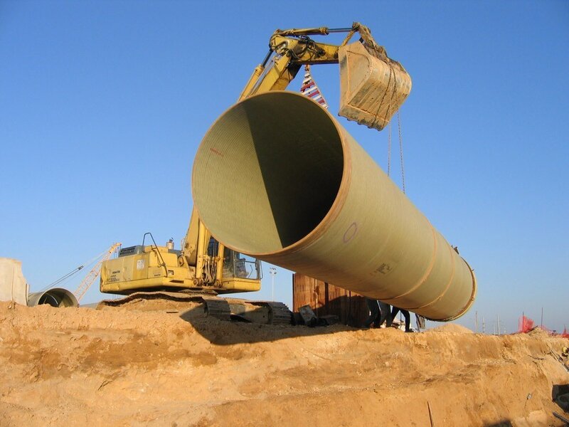 Excavator lifting large pipe