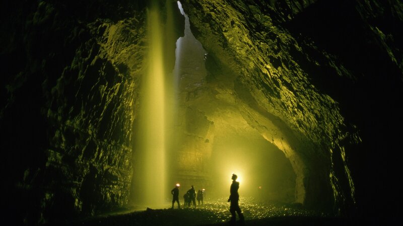 Explorers in a cave with waterfall