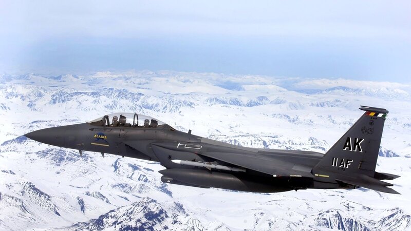F-15 fighter jet over snowy mountains