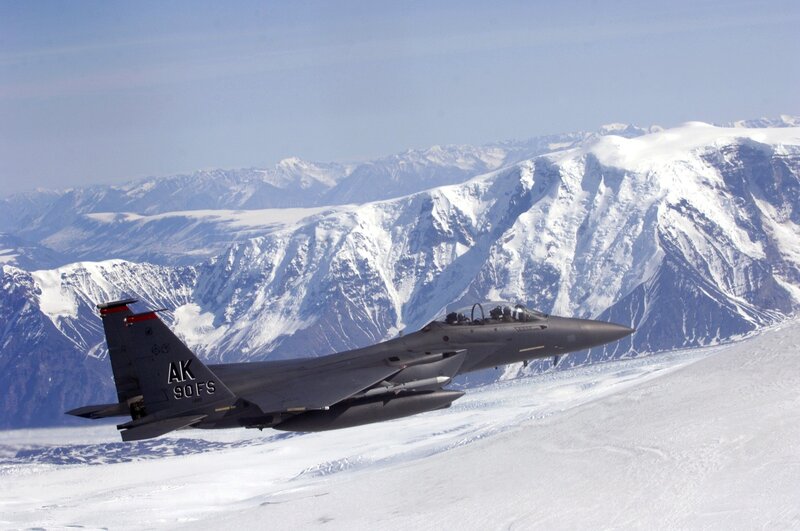 F-15 fighter jet over snowy mountains