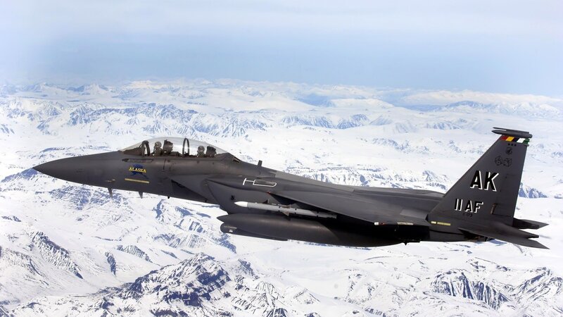 F-15 fighter jet over snowy mountains