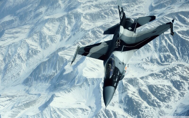 F-16 fighter jet over snowy mountains