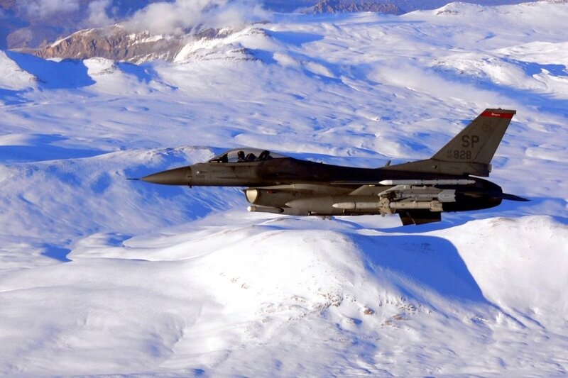F-16 fighter jet over snowy mountains