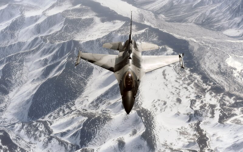F-16 fighter jet over snowy mountains