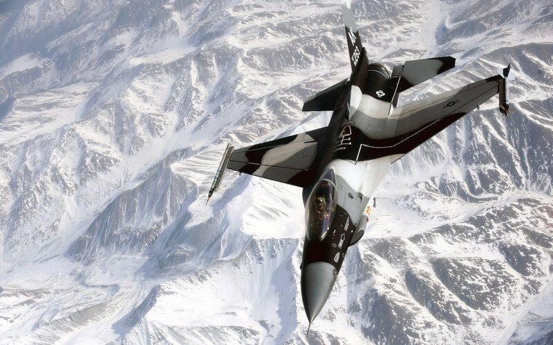 F-16 fighter jet over snowy mountains