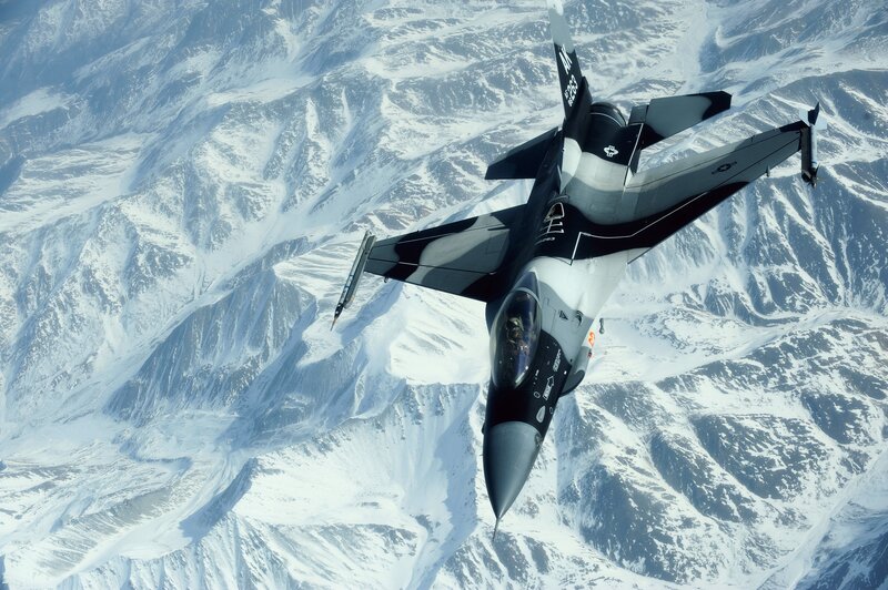 F-16 fighter jet over snowy mountains