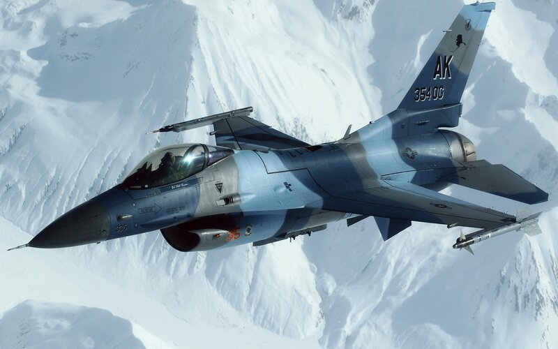 F-16 fighter jet over snowy mountains