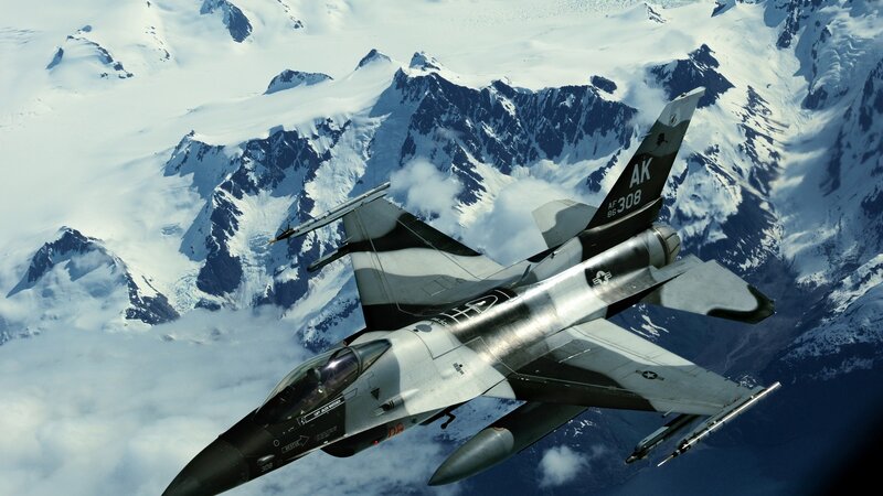 F-16 fighter jet over snowy mountains
