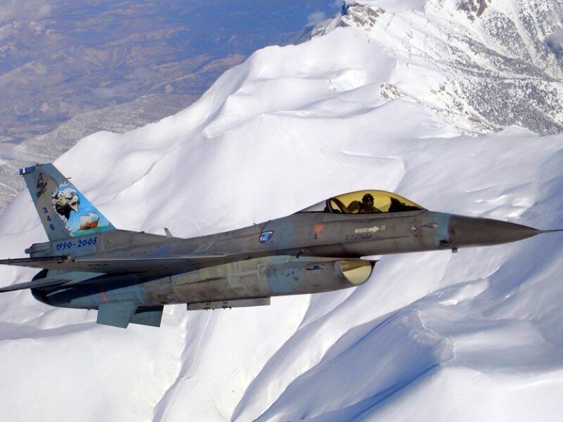 F-16 fighter jet over snowy mountains