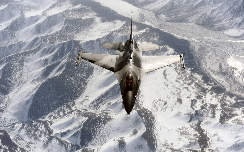 F-16 fighter jet over snowy mountains