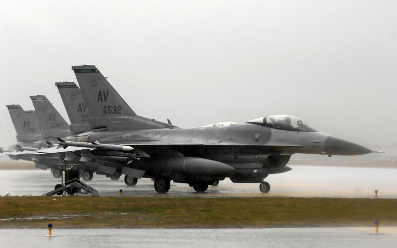 F-16 fighter jets on wet tarmac